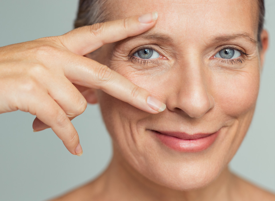 An elderly woman showing her eye with index and middle fingers