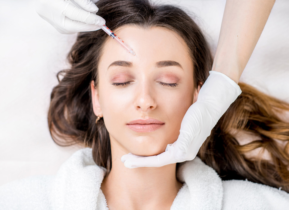 An woman being injected with syringe on her forhead with closed eyes